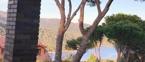 Vista de un edificio con una chimenea de ladrillo, rodeado de árboles y una masa de agua al fondo.