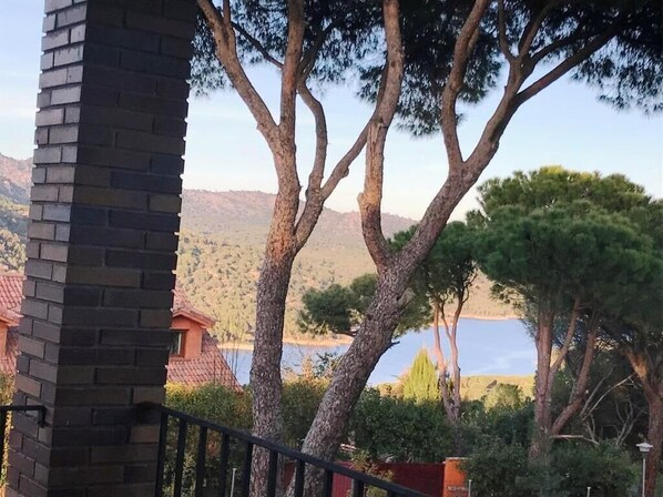 Vista de un edificio con una chimenea de ladrillo, rodeado de árboles y una masa de agua al fondo.