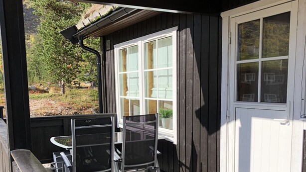 A covered outdoor area with a wooden deck, two chairs, and a table. - Randsverk Hytter i Lemonsjøen Fjellpark (Vaga)