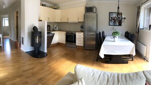 A modern kitchen with a dining area, wooden flooring, and a large window. - Randsverk Hytter i Lemonsjøen Fjellpark (Vaga)