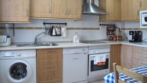 Una cocina con armarios de madera, lavavajillas, horno y microondas.