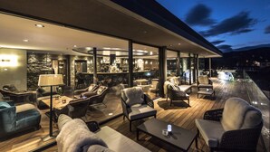 A modern outdoor lounge area with sofas, chairs, and a bar.