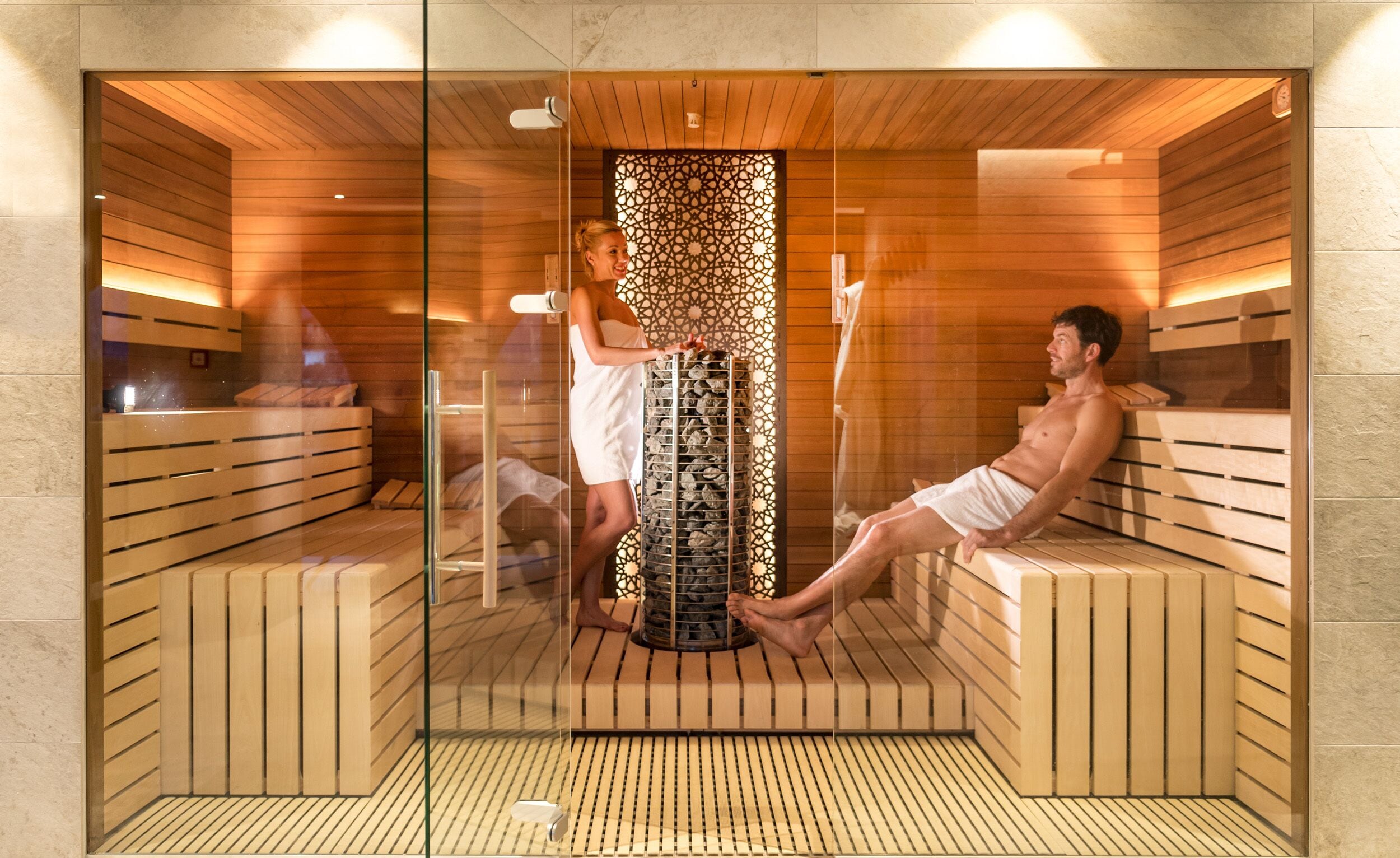A sauna room with wooden benches and a central stone heater.