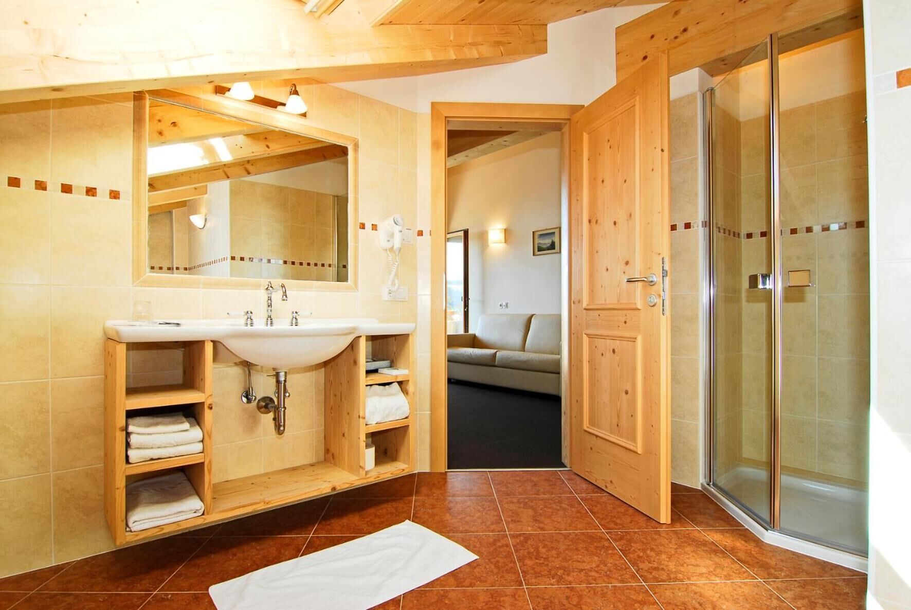 A bathroom with a wooden vanity, a sink, and a glass shower enclosure.