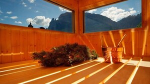 A wooden cabin with a large window offering a mountain view.