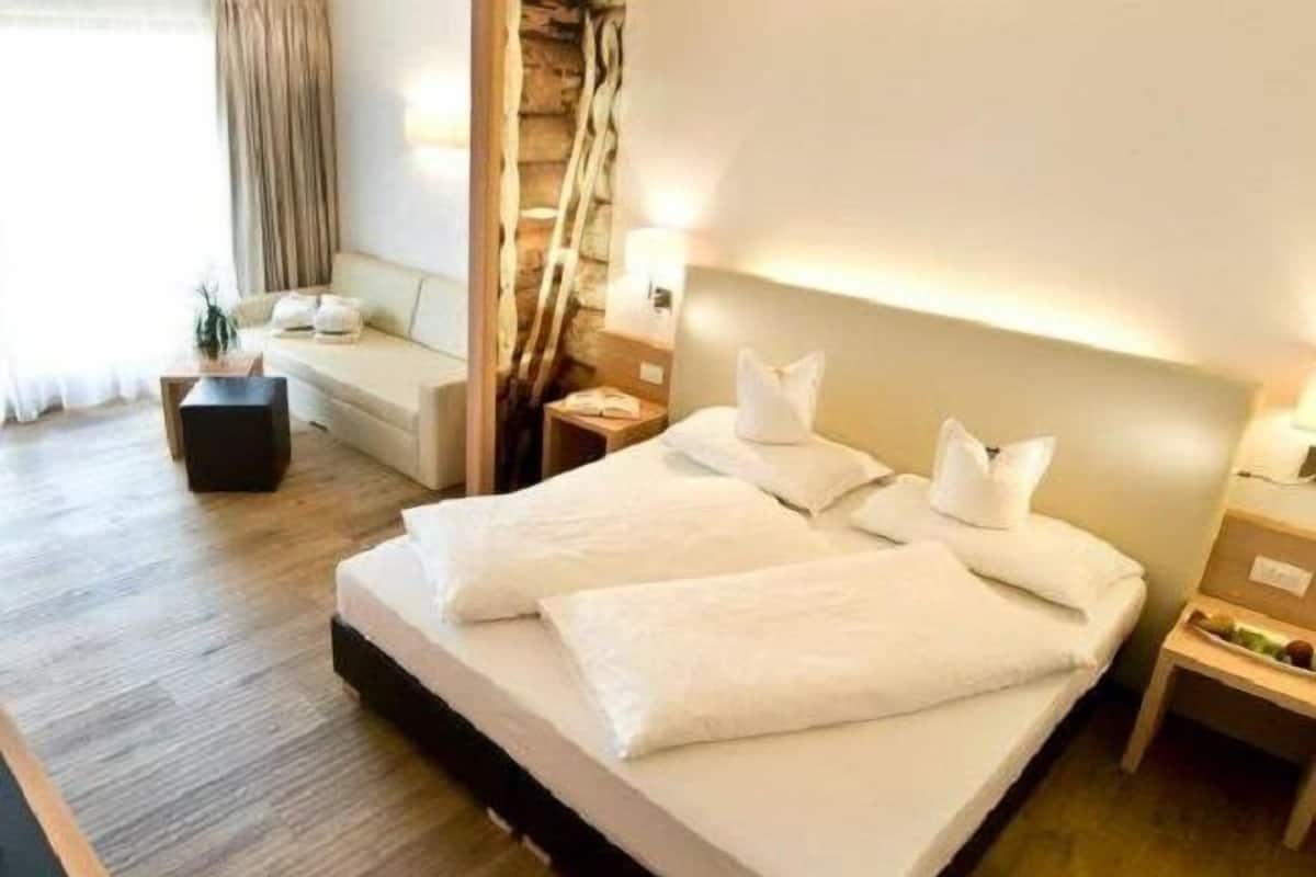 A neatly made double bed with white linens, a wooden headboard, and bedside tables with lamps.