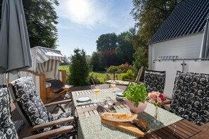 Eine Terrassengruppe im Freien mit Tisch für zwei Personen, umgeben von Stühlen mit gemusterten Kissen.