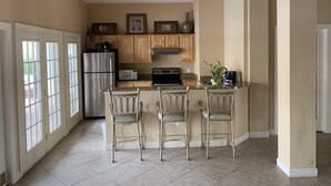 A kitchen with a central island, bar stools, a refrigerator, microwave, stove, and wooden cabinets.