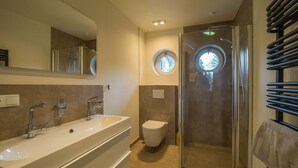 Un baño moderno con un lavamanos grande, inodoro y ducha a ras de suelo.