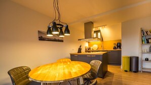 Una cocina moderna con una mesa redonda de madera y sillas de cuero, un horno empotrado y una cafetera.