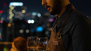 A person serving drinks at a table with a cityscape in the background.