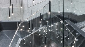 A modern interior with a glass railing, geometric patterned floor, and a central seating area. - Hotel Nodo - El primer hotel de negocios en Chile (Santiago)