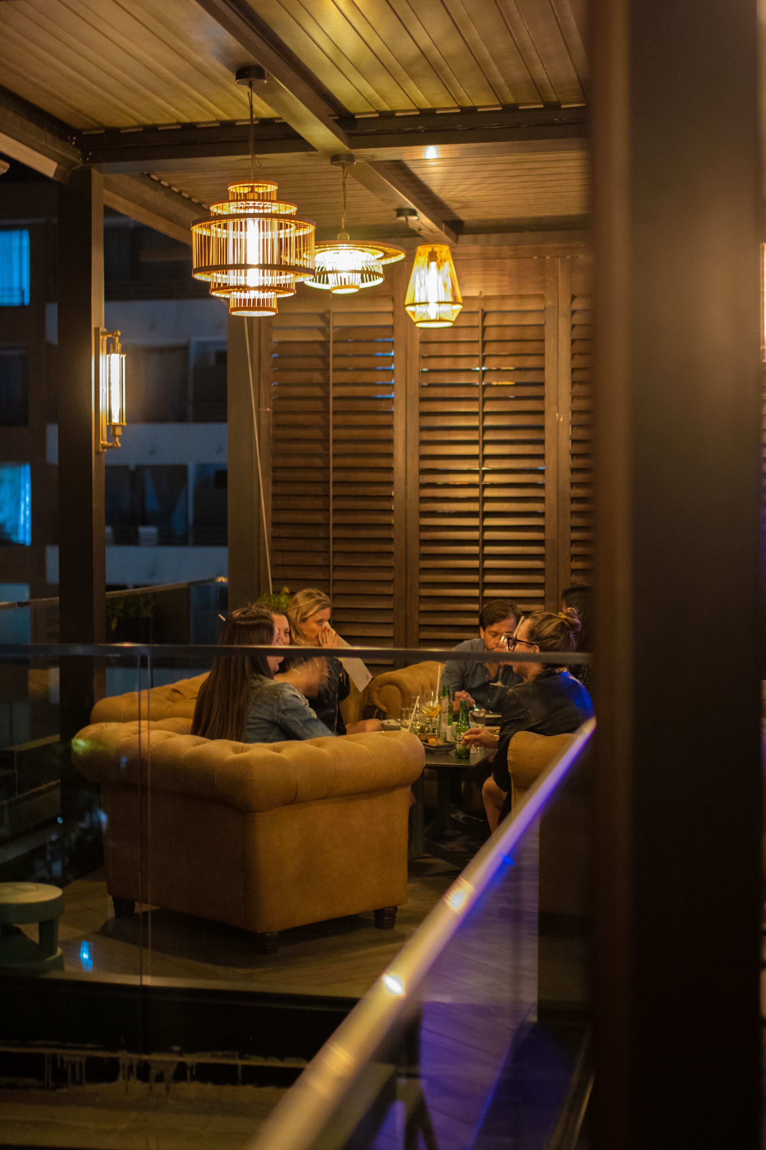 A cozy lounge area with a sofa and a coffee table, wooden ceiling, and pendant lighting.