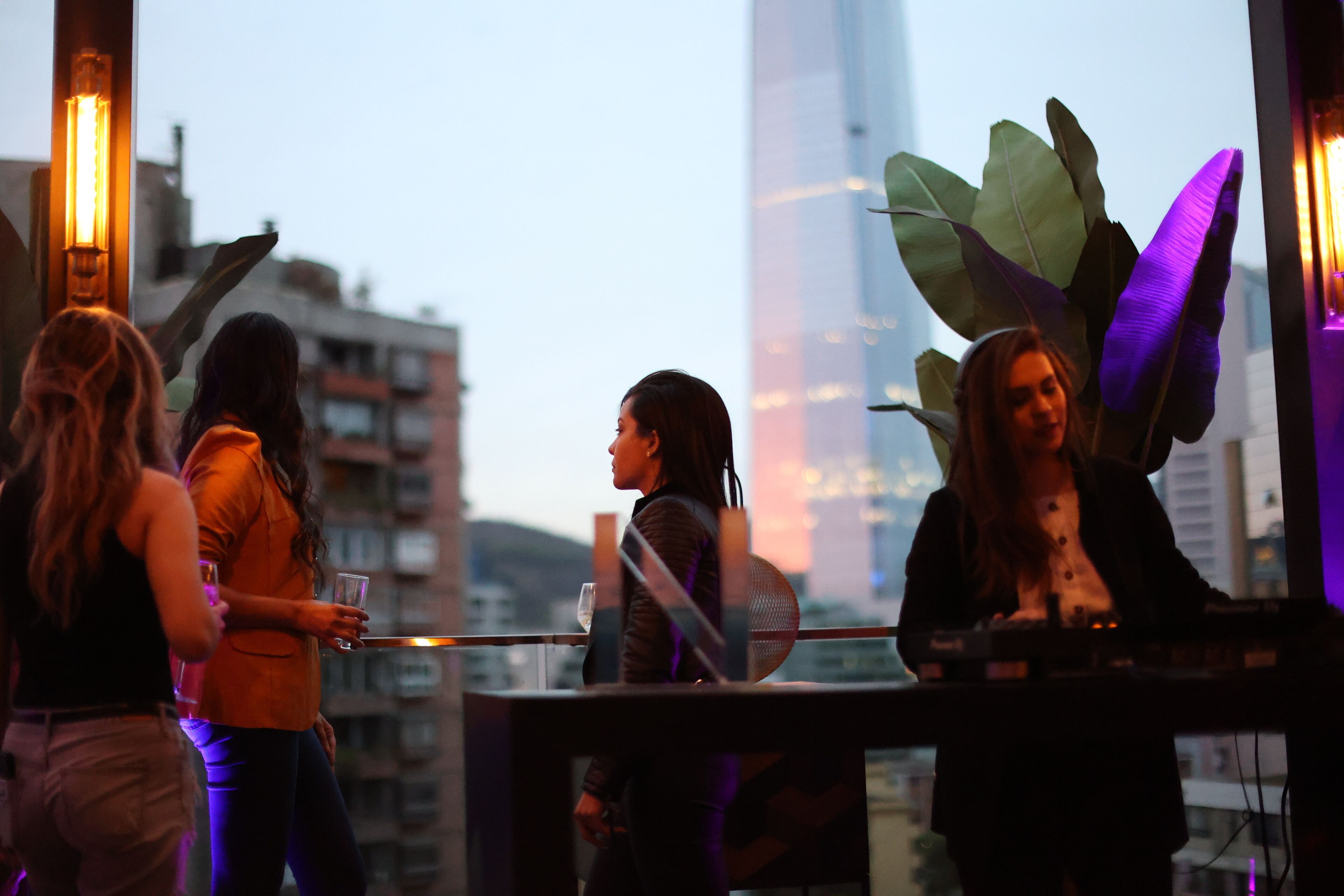A group of people at a bar with a city view in the background.