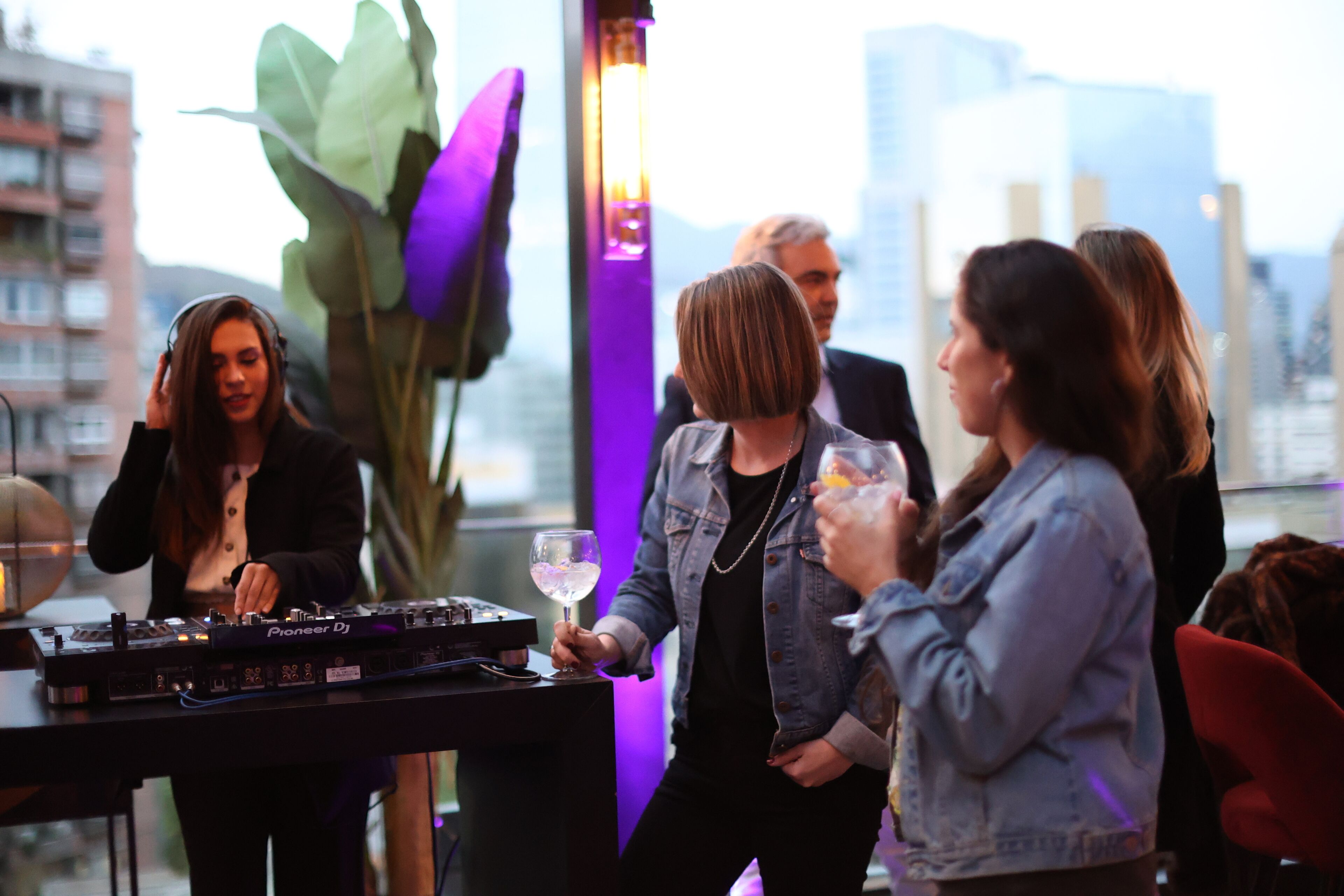 A group of people at a DJ booth with a city view in the background.