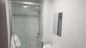 A modern bathroom with a glass-enclosed shower, a white sink, and a mirror. - The Kingstanding Inn (Birmingham)