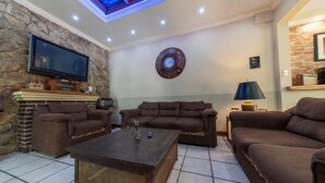 Un salon avec un mur en pierre, un téléviseur à écran plat, une cheminée et une horloge murale ronde.