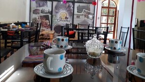 Un coin repas avec une table en verre, des tasses blanches à pois bleus et un sucrier en verre.