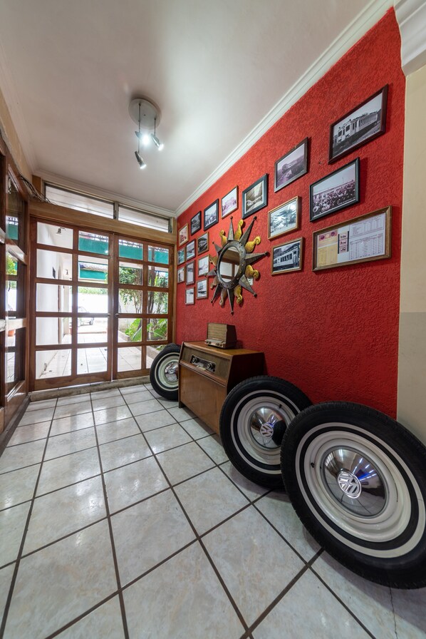 Een hal met een rode wand, ingelijste foto's, een zon decoratie en een bandenpresentatie.