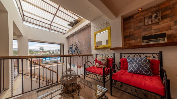 Un vaste espace de vie avec balcon, un ensemble de canapés rouges, une table basse en bois et une grande fenêtre donnant sur l’extérieur.