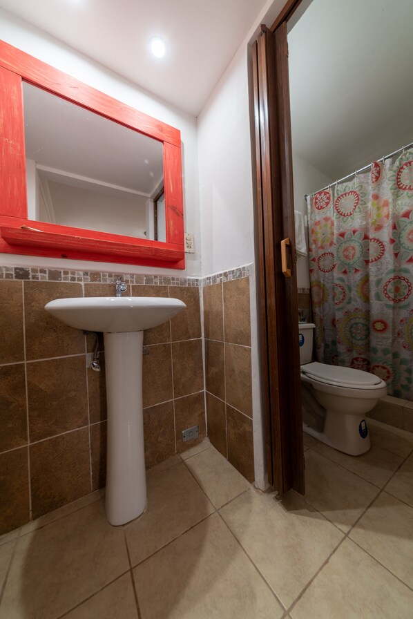A bathroom with a white sink, a toilet, and a shower curtain. - Hotel Canada (Quetzaltenango)