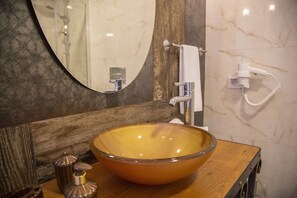 Un baño con tocador de madera, un lavamanos ovalado grande, un espejo y un perchero para toallas.