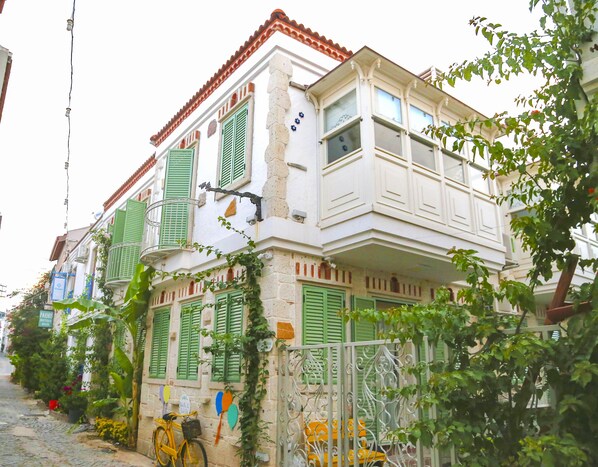 Un edificio tradicional con contraventanas verdes, un balcón y una calle empedrada.