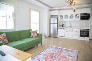 Una cocina moderna con armarios blancos, un refrigerador de acero inoxidable y un horno empotrado.