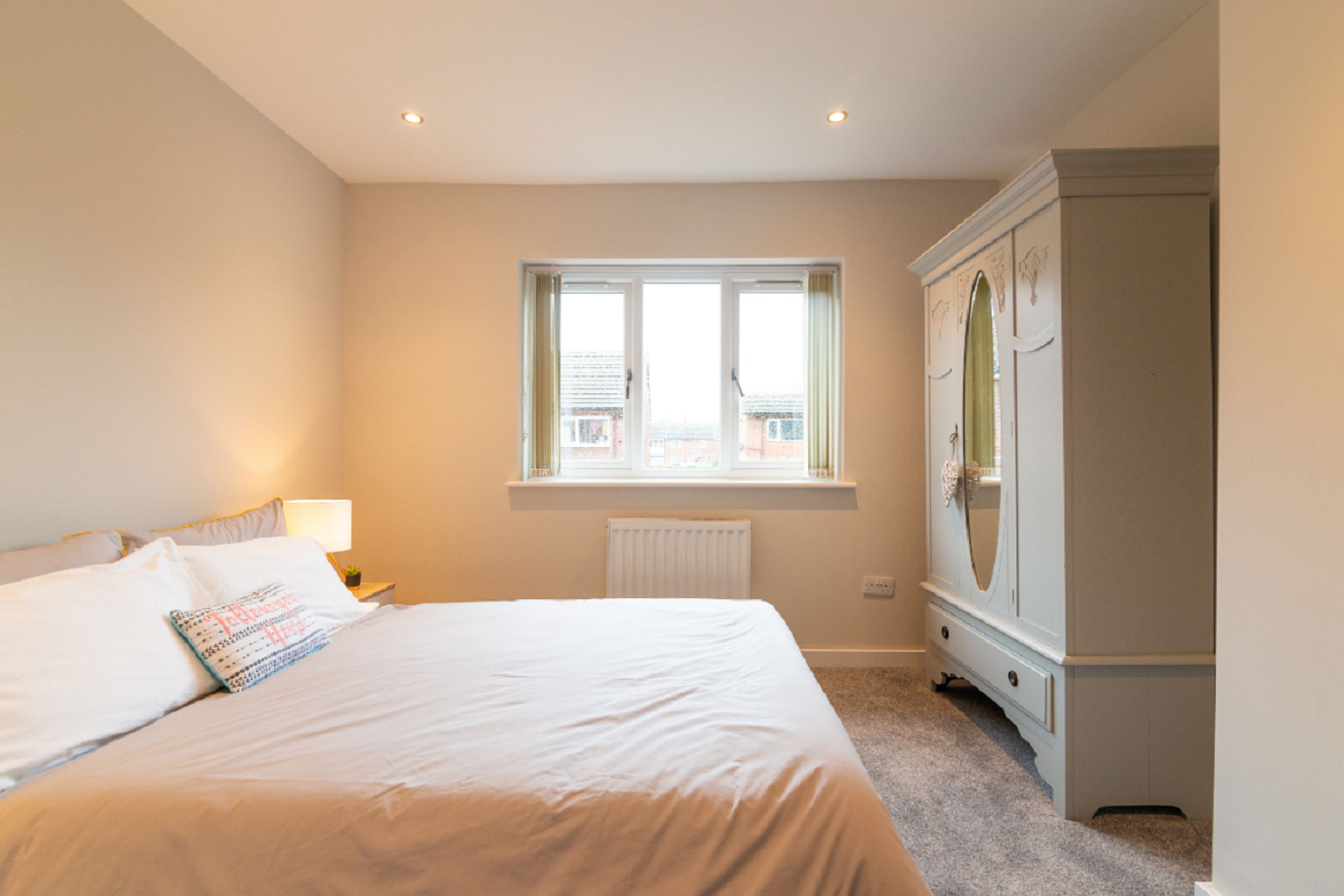 Une chambre à coucher avec un lit, une fenêtre, un radiateur et une armoire.