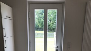 A room with a white door, a small window, and a black mat at the entrance. - Modern apartment in a quiet location for 4 persons (Brietlingen)