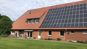 A house with a sloped roof, solar panels, a brick exterior, and a well-maintained lawn. - Modern apartment in a quiet location for 4 persons (Brietlingen)