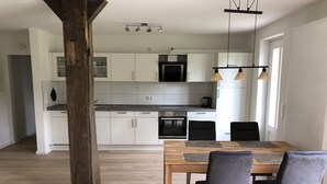 A modern kitchen with white cabinets, a wooden dining table, and two chairs. - Modern apartment in a quiet location for 4 persons (Brietlingen)