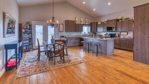 A spacious kitchen with wooden cabinets, a central island, and a chandelier. - Wild Cat Cabin - Hot Tub - Foosball - Near Resort (Driggs)