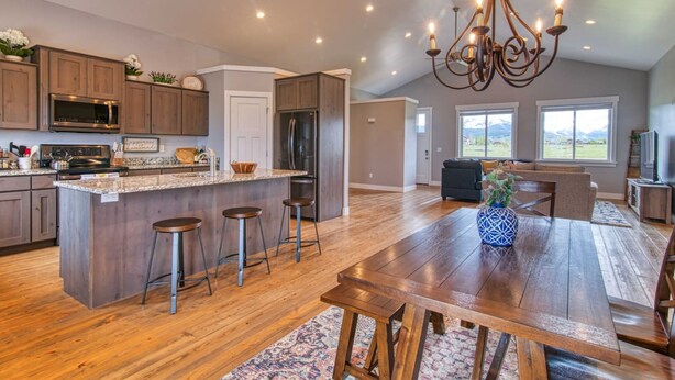 A spacious kitchen with a large island, wooden bar stools, and a chandelier. - Wild Cat Cabin - Hot Tub - Foosball - Near Resort (Driggs)