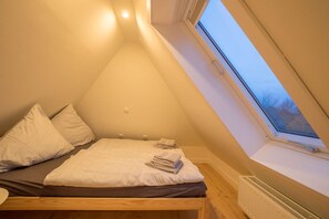 Cozy attic retreat with a single bed, bedside table, and window offering a view of the outside.