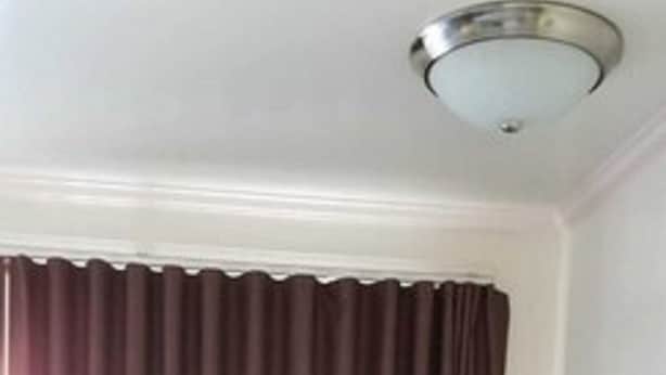 Ett hotellrum med en säng, ett skrivbord, en stol och ett fönster med gardiner.