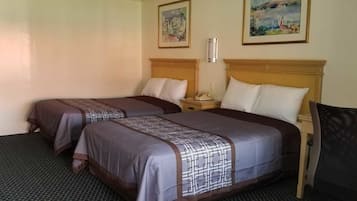 Ein Hotelzimmer mit zwei Betten, einem Nachttisch, einem Sessel und zwei Bildern an der Wand.
