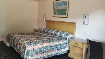 A hotel room with a bed, a desk, a chair, a nightstand, and a painting on the wall.