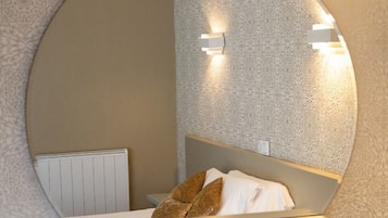 A circular mirror with a bed and wall-mounted lights.