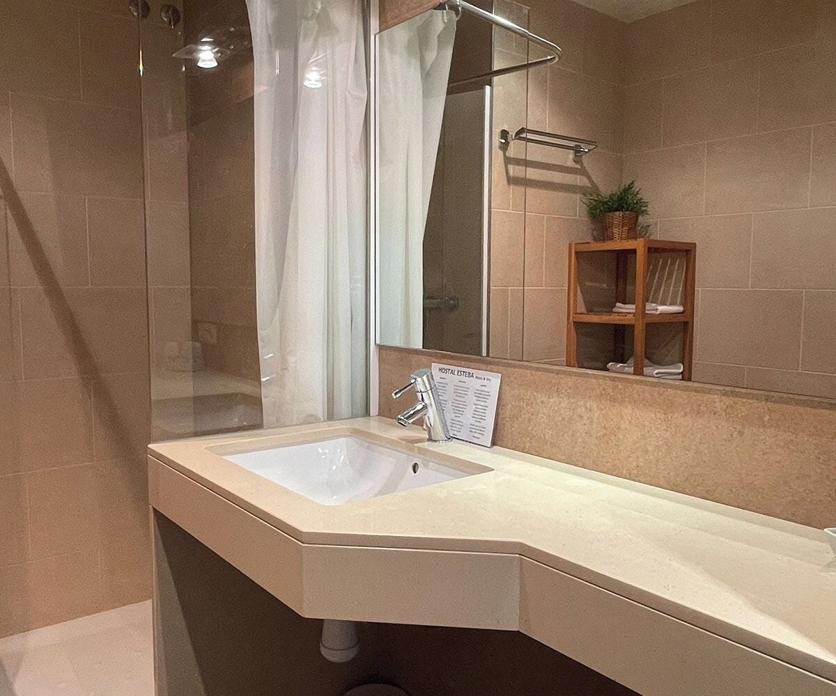 Un baño moderno con cabina de ducha de vidrio, lavamanos y espejo.