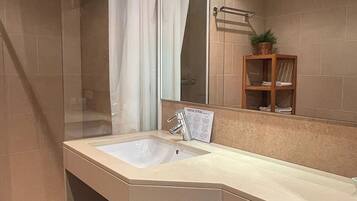 Un baño moderno con cabina de ducha de vidrio, lavamanos y espejo.