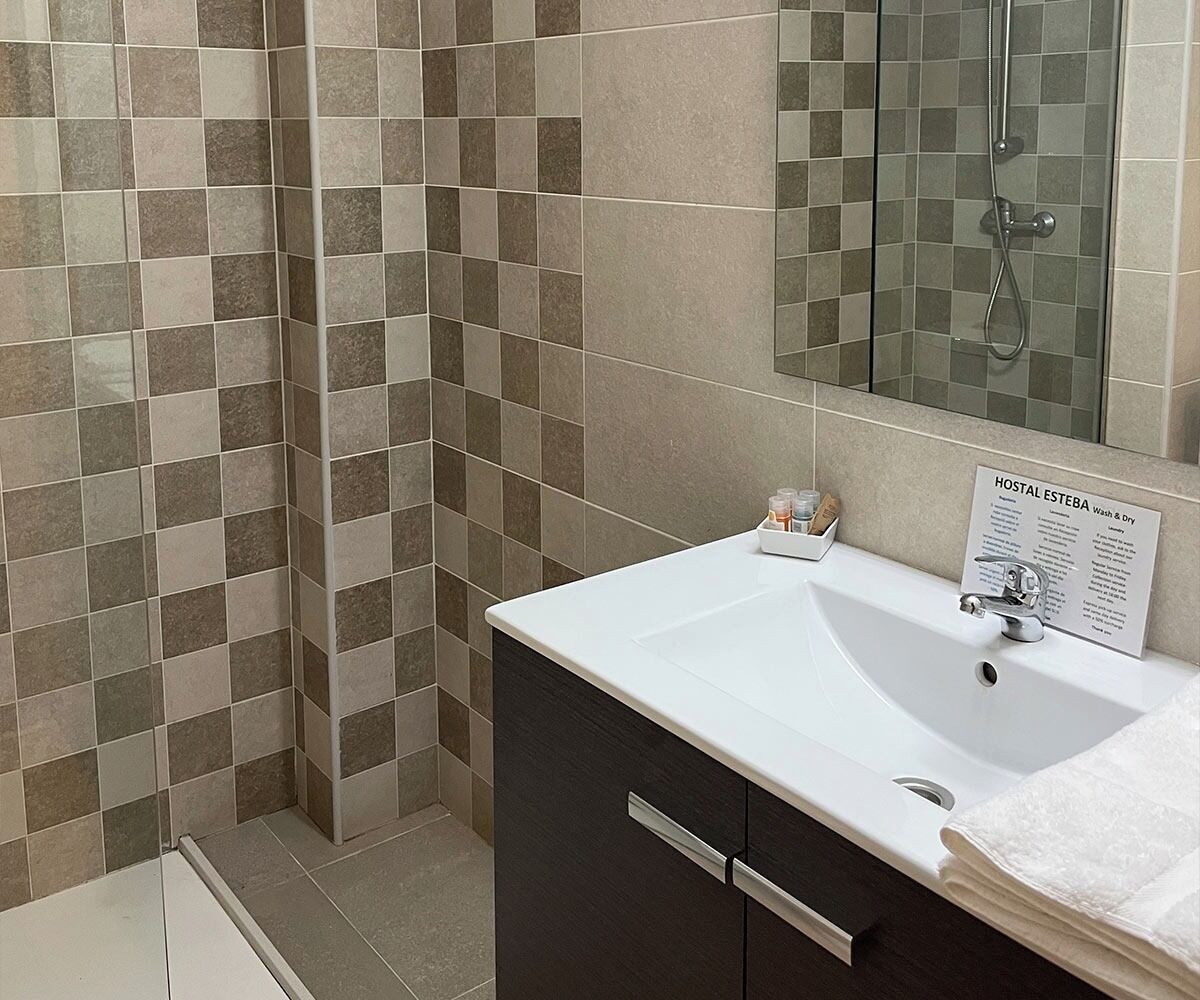 A bathroom with a white sink, dark cabinets, and a shower area.