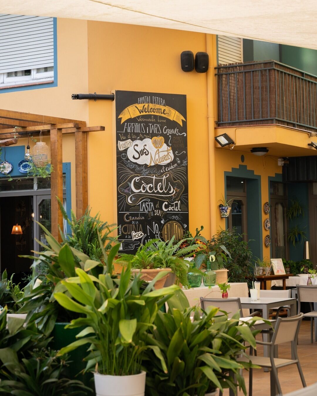 Un área de estar al aire libre con un cartel de pizarra que anuncia cócteles y licor de vermut.
