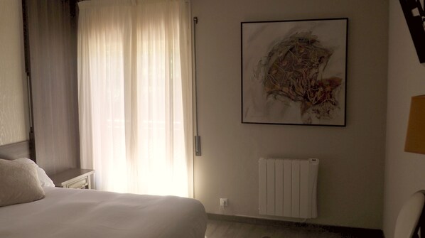 A hotel room with a bed, a radiator, and a large abstract painting on the wall. - Hostal Esteba (Caldes de Malavella)