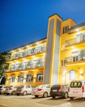 Un hotel a più piani con balconi e un'area parcheggio.