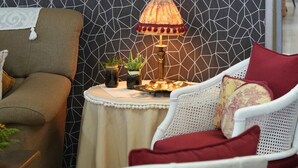 A room with a geometric patterned wall, a framed photograph, a table with a lamp, and two chairs. - Hostal Esteba (Caldes de Malavella)