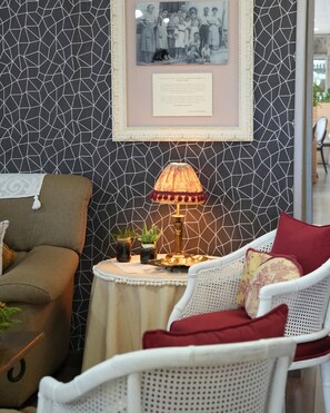 A room with a geometric patterned wall, a framed photograph, a table with a lamp, and two chairs. - Hostal Esteba (Caldes de Malavella)
