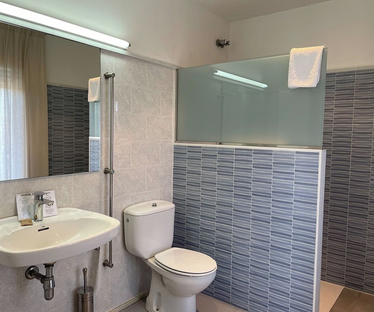 Un baño moderno con un lavabo blanco, un inodoro y una cabina de ducha con paredes de vidrio.