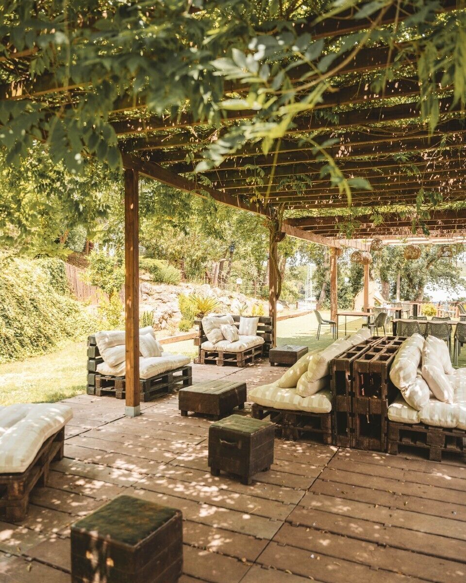 An outdoor patio with wooden furniture and a pergola structure.