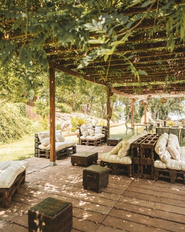 An outdoor patio with wooden furniture and a pergola structure.